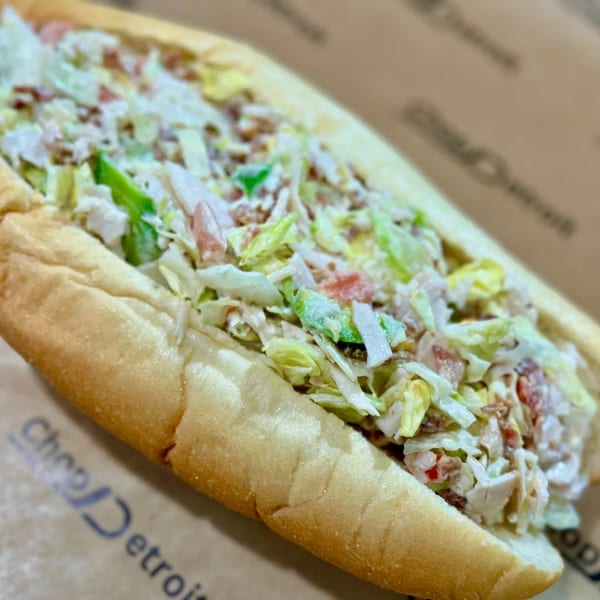 A close-up of a Chop Detroit sandwich, filled with chopped meat, lettuce, and sauce.