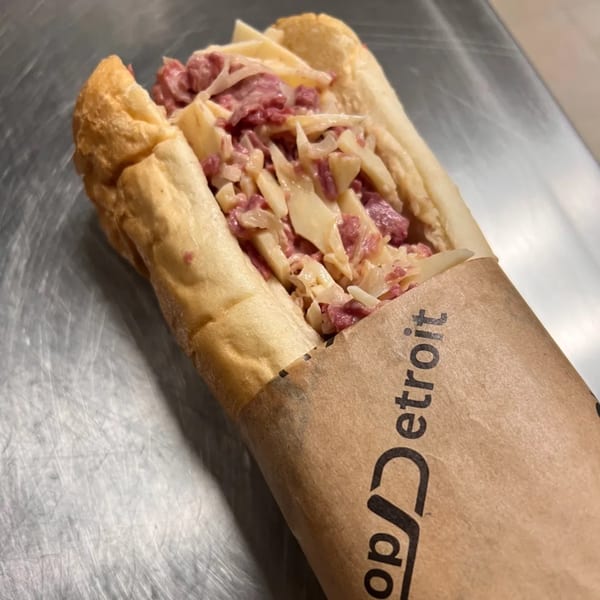 A Chop Detroit sandwich, filled with corned beef and Swiss cheese, wrapped in branded paper.