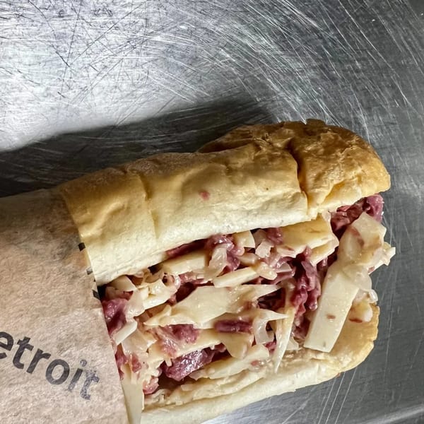 A Chop Detroit sandwich with corned beef and coleslaw on a hoagie roll, partially wrapped in paper.